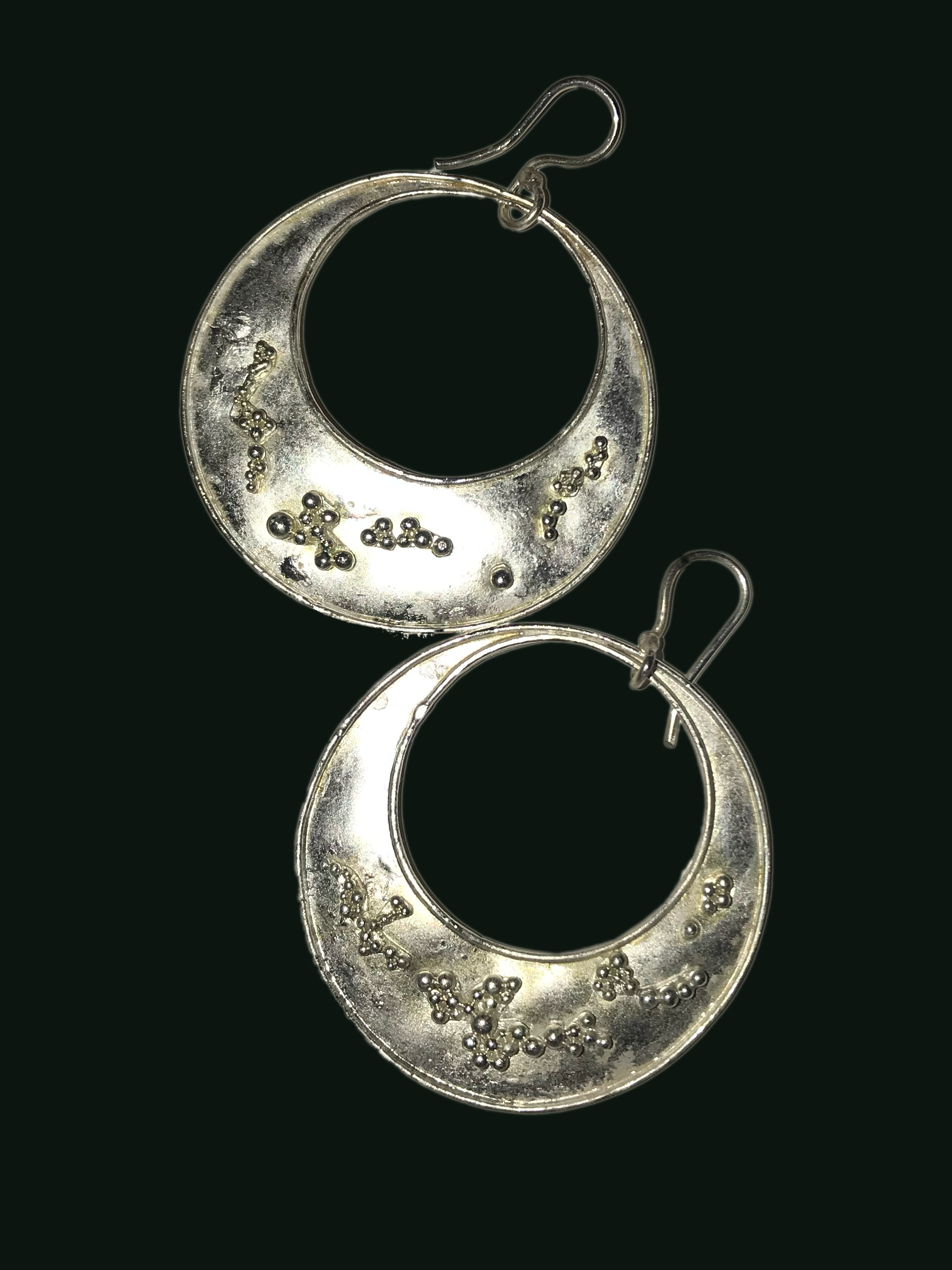 Photograph of a pair of round earrings designed and handmade by me, they have silver granulation.